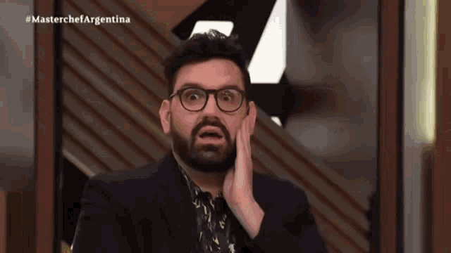 a man with glasses and a beard is making a surprised face in front of a masterchef argentina sign