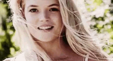 a woman with long blonde hair is smiling and looking at the camera .