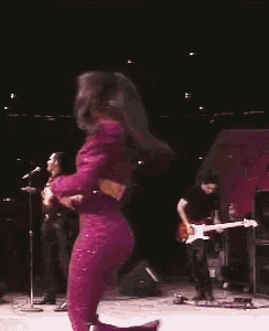 a woman in a purple suit is singing into a microphone