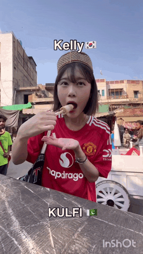 a girl wearing a red shirt that says kelly is eating food
