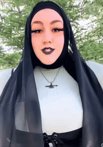 a woman wearing a black scarf and a necklace with a bird on it
