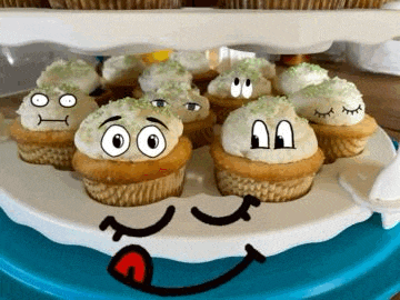a tray of cupcakes with faces drawn on them on a blue plate .