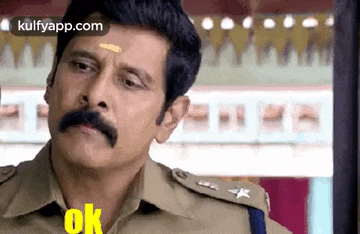 a man with a mustache is wearing a police uniform and making a face .
