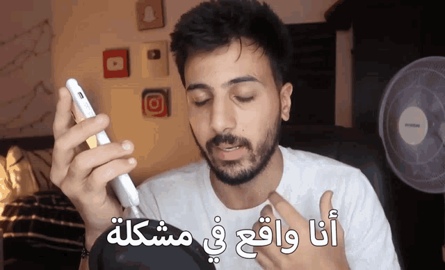 a man with a beard is talking on a cell phone with arabic writing on the screen