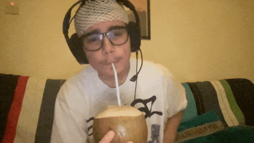 a man with a bandage on his head drinks from a coconut through a straw