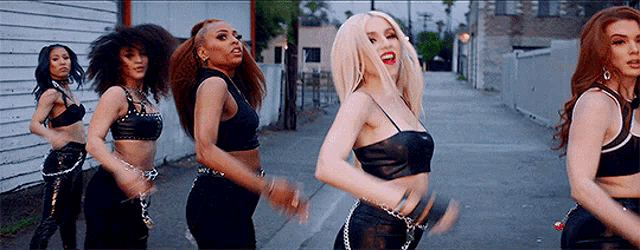 a group of women are dancing together on a sidewalk .