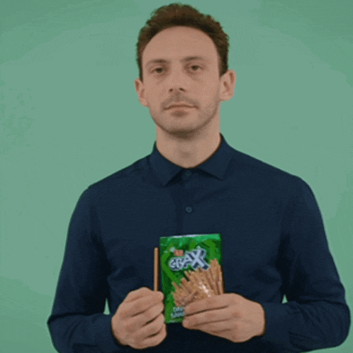 a man in a blue shirt is holding a bag of grax