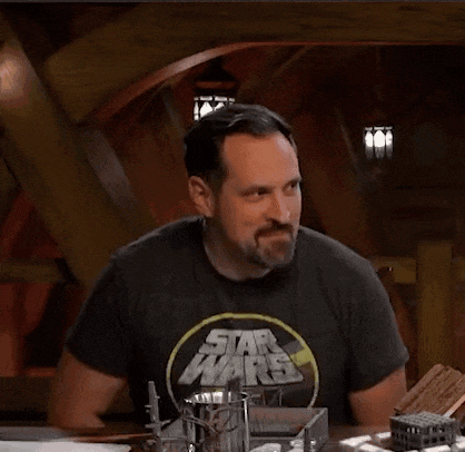 a man wearing a black star wars t-shirt is sitting at a table