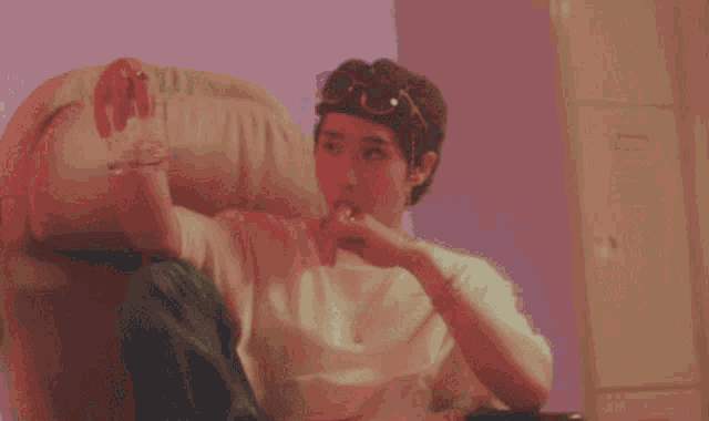 a man in a white shirt sits in a chair with a green light coming out of his foot