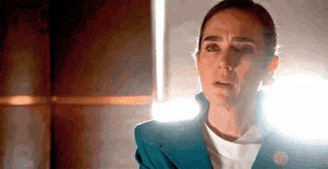 a woman in a blue suit and white shirt is crying in a dark room .