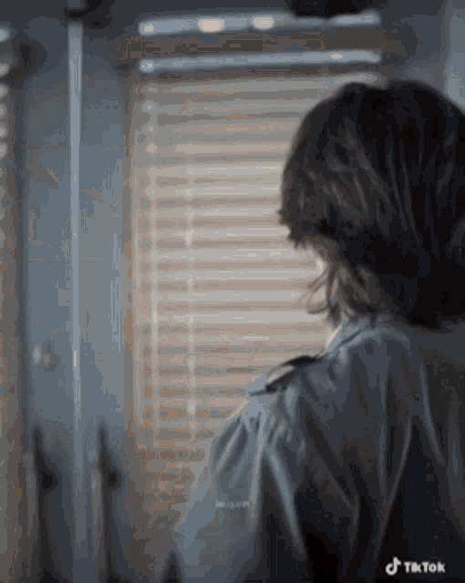 a woman in a police uniform is standing in front of a window .