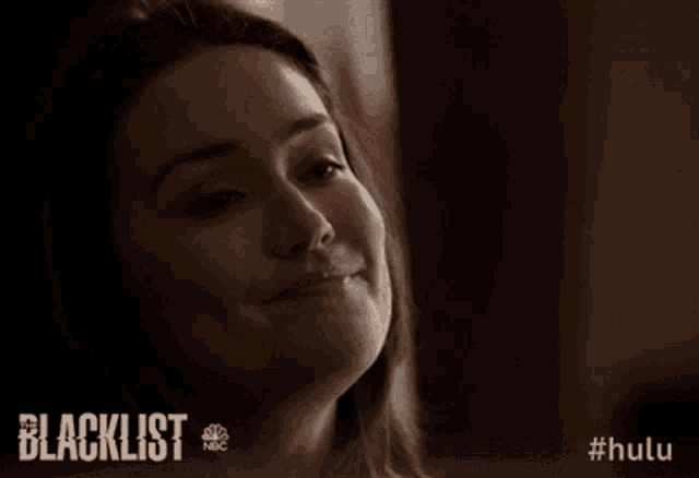 a woman is smiling in front of a blacklist ad
