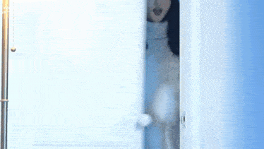 a woman in a sweater is standing in a doorway and talking .