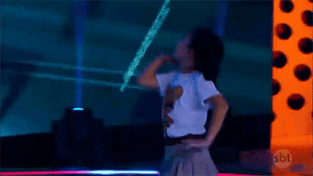 a young girl is dancing on a stage with her arms in the air .
