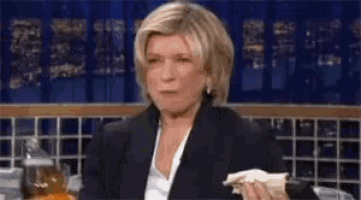 a woman in a suit is holding a napkin and making a face .