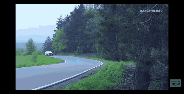 a car is driving down a curvy road in the woods ..