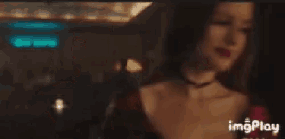 a woman in a red dress is talking to another woman in a dark room