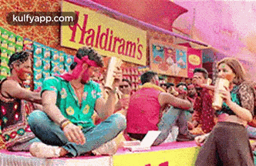 a group of people are sitting on top of a table in front of a sign that says haldiram 's .