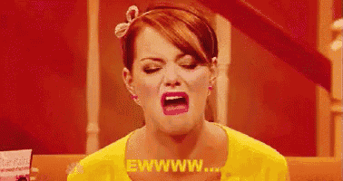 a woman in a yellow shirt is making a funny face with her mouth wide open .