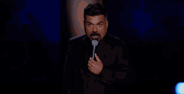 a man with a mustache is holding a microphone in front of him