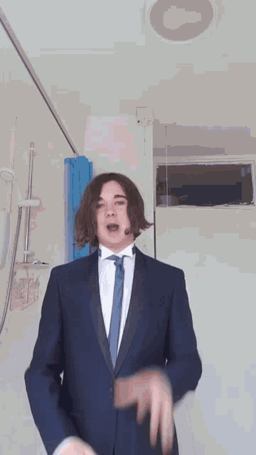 a man in a tuxedo and tie is standing in front of a shower
