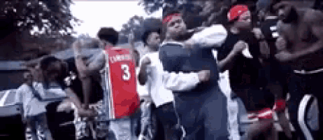 a group of young men are dancing in a parking lot . one of the men is wearing a jersey that says 3 .