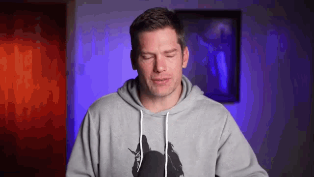 a man wearing a grey hoodie with a picture of a bat on it