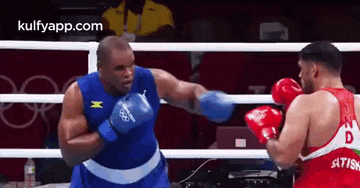two boxers are fighting in a boxing ring and one of them is wearing a blue shirt with the letter x on it .