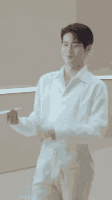 a man in a white shirt and khaki pants is standing in front of a wall .