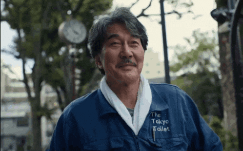 a man wearing a blue jacket that says the tokyo toilet on the front