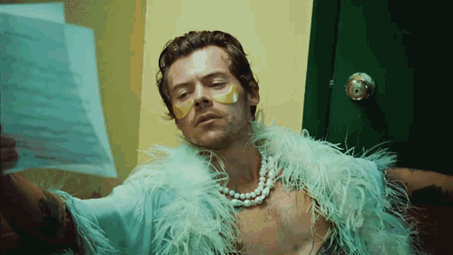 a man wearing feathers and a pearl necklace is looking at a piece of paper