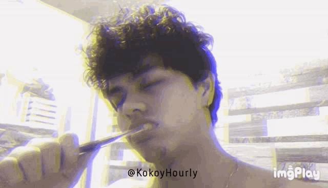 a young man brushing his teeth with the hashtag kokoyhourly on the bottom