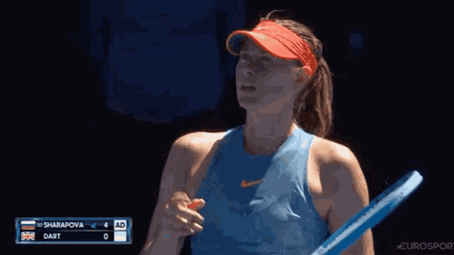 a woman in a blue tank top is holding a tennis racquet in her hand .