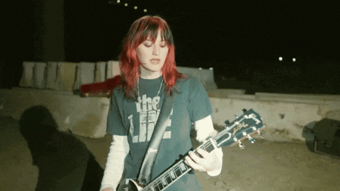 a girl with red hair is playing a guitar with a shirt that says the life on it