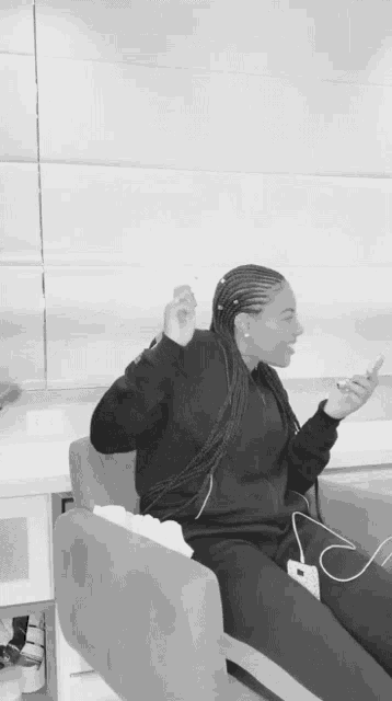 a black and white photo of a woman sitting in a chair with her hands in the air