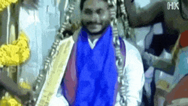 a man with a blue scarf around his neck is smiling while holding a gold bar .