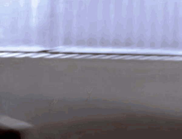 a person is laying on a bed in front of a window with a white curtain .