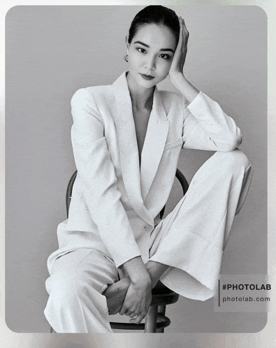 a woman in a suit sits on a chair with her legs crossed