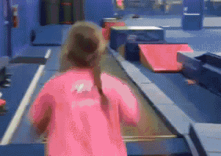 a girl in a pink shirt is running on a track
