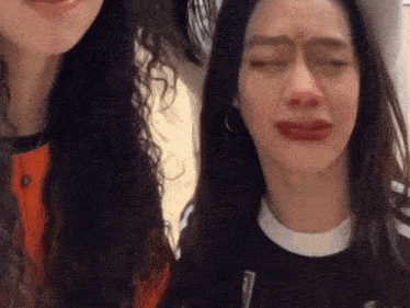 two women are making funny faces with their eyes closed and one is crying