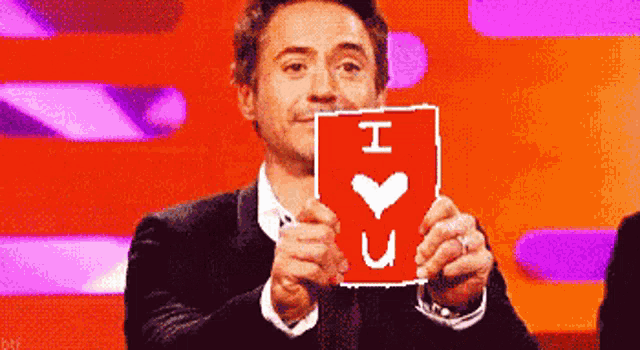 a man in a suit is holding up a sign that says i love you