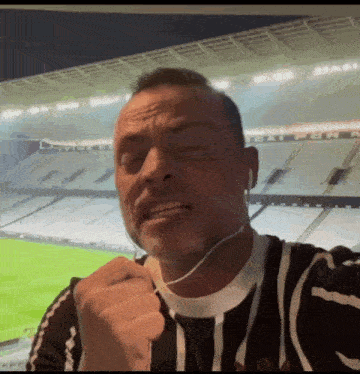 a man wearing ear buds stands in front of a soccer field
