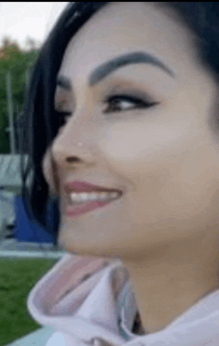a close up of a woman 's face smiling and looking at the camera .