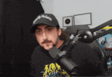 a man wearing a black hat that says georgia on it is sitting in front of a microphone