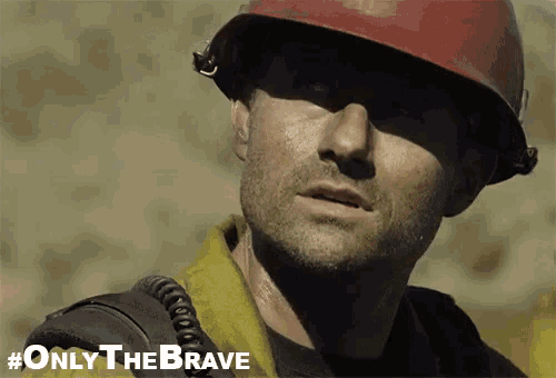 a man wearing a red hard hat and a yellow shirt with #only the brave written on the bottom