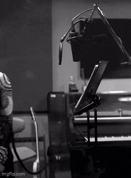 a black and white photo of a person singing into a microphone in a recording studio