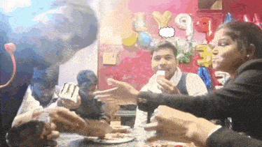 a group of people gathered around a table with balloons and a speech bubble that says ' y9 '