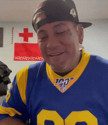 a man wearing a rams jersey and a hat is smiling