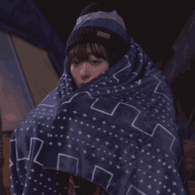 a woman wrapped in a blue blanket has a label on her hat that says mountain