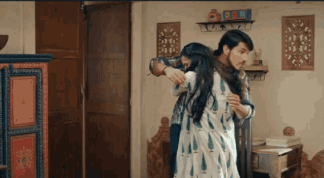 a man and a woman are hugging in a room with a clock on the wall